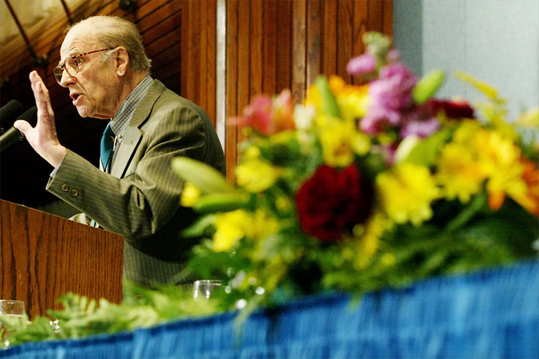盖洛德·纳尔逊在地球日活动中站在讲台上讲话的照片