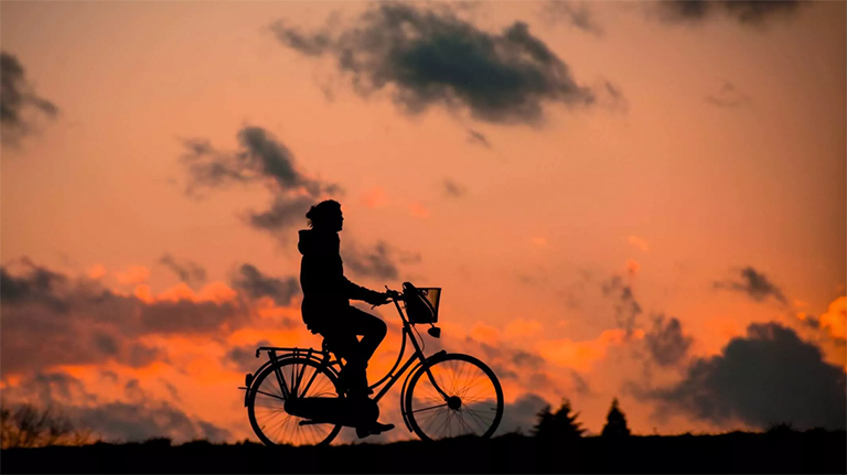 在日落的天空中骑自行车的人的轮廓